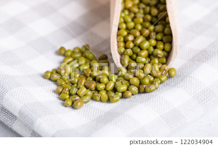 Mung beans in wooden scoop on cotton napkin, close up Mung beans in wooden scoop on cotton napkin, close up 122034904