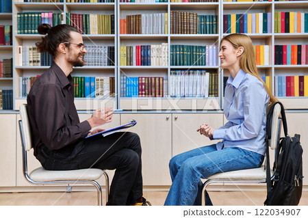Teenage student girl talking with male teacher, social worker, school counselor in library 122034907