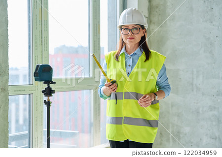 Portrait confident woman in safety vest hard hat at construction site Portrait confident woman in safety vest hard hat at construction site 122034959