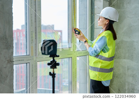 Industrial worker, woman measuring window with tape measure at construction site Industrial worker, woman measuring window with tape measure at construction site 122034960
