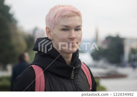 Traveler woman with short hair smiling, standing and looking at camera, outdoors portrait Traveler woman with short hair smiling, standing and looking at camera, outdoors portrait 122034992