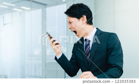A man/businessman yelling loudly at his smartphone A man/businessman yelling loudly at his smartphone 122035383