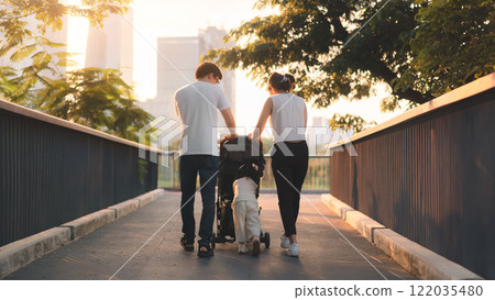 Asian Family Strolling with Baby in Stroller During Sunset in Urban Park Setting Asian Family Strolling with Baby in Stroller During Sunset in Urban Park Setting 122035480