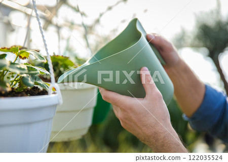 Greenhouse workers watering flowers in a glasshouse Greenhouse workers watering flowers in a glasshouse 122035524