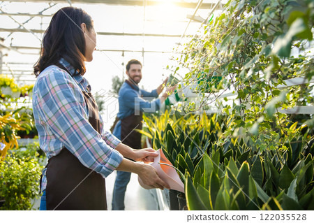 Greenhouse workers watering flowers in a glasshouse 122035528