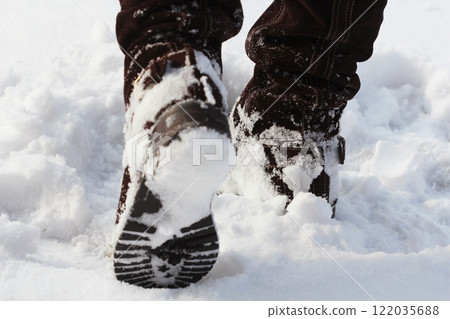 Active woman walking away from the camera through winter snow wearing pale pink boots in the countryside 122035688