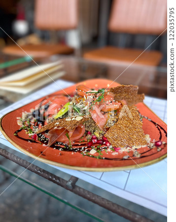 Food platter features a combination of salmon, quinoa, pomegranate seeds and crispbread. Vibrant ingredients and artistic plating create a gourmet, festive dining experience 122035795