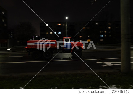 An old fire truck driving through the city at night, side view. Motion blur An old fire truck driving through the city at night, side view. Motion blur 122036142
