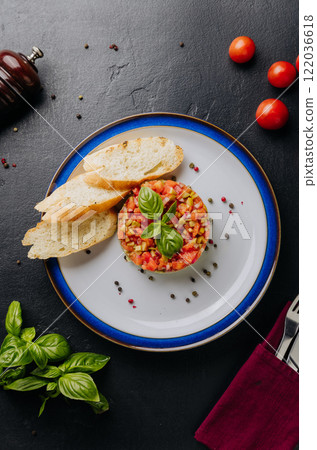 Guacamole tartare with fresh vegetables, basil garnish, and crispy baguette slices on a white plate Guacamole tartare with fresh vegetables, basil garnish, and crispy baguette slices on a white plate 122036618
