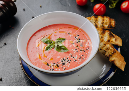 Fresh tomato soup with sesame seeds, basil garnish, and toasted bread for a comforting meal 122036635