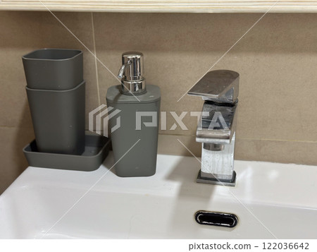 Sleek modern bathroom sink with a chrome faucet and neatly placed accessories. Clean and minimalist setting highlights functionality and elegance in home interiors 122036642