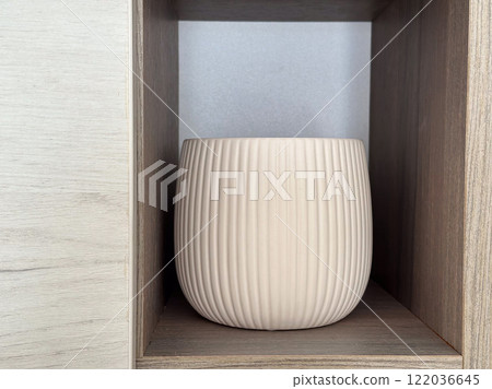 White ceramic vase displayed on a wooden shelf. Clean and textured surface offers a modern yet timeless design for interior decor White ceramic vase displayed on a wooden shelf. Clean and textured surface offers a modern yet timeless design for interior decor 122036645
