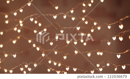 Warm string lights shaped like hearts illuminate a cozy indoor space during an evening gathering 122036679