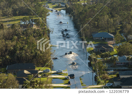 Hurricane flooded street with moving cars and surrounded with water houses in Florida residential area. Consequences of natural disaster 122036779