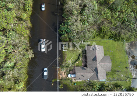 Hurricane Ian flooded street with moving cars and surrounded with water houses in Florida residential area. Consequences of natural disaster Hurricane Ian flooded street with moving cars and surrounded with water houses in Florida residential area. Consequences of natural disaster 122036790