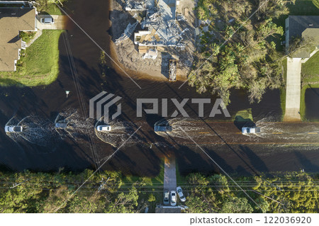 Flooded american street with moving vehicles and surrounded with water houses in Florida residential area. Consequences of hurricane natural disaster Flooded american street with moving vehicles and surrounded with water houses in Florida residential area. Consequences of hurricane natural disaster 122036920