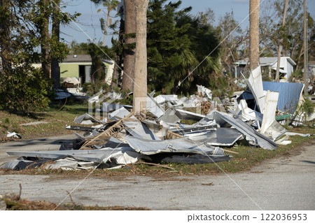 Heaps of debris rubbish on street side near severely damaged by hurricane houses in Florida mobile home residential area. Consequences of natural disaster Heaps of debris rubbish on street side near severely damaged by hurricane houses in Florida mobile home residential area. Consequences of natural disaster 122036953