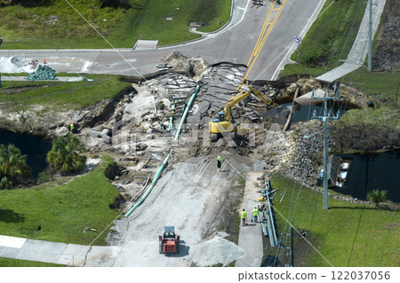 Construction equipment at roadworks site. Reconstruction of damaged road bridge destroyed by river after flood water washed away asphalt. Rebuilding of ruined transportation infrastructure 122037056