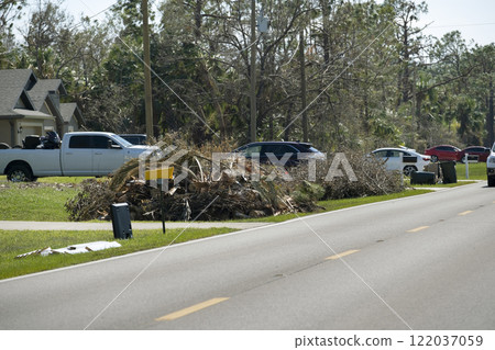 Cut down and fallen trees branches disposed in heaps on street side after hurricane severely damaged houses in Florida mobile home residential area. Consequences of natural disaster 122037059