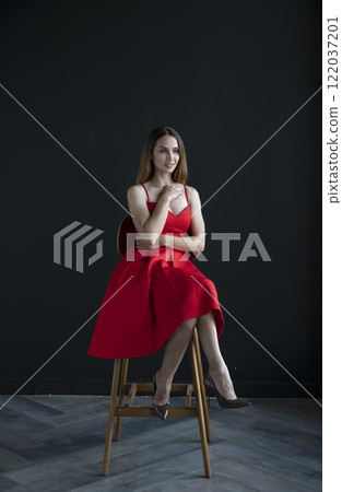 portrait of a beautiful young woman in a red dress, studio shot on a dark background portrait of a beautiful young woman in a red dress, studio shot on a dark background 122037201
