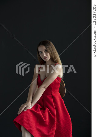 portrait of a beautiful young woman in a red dress, studio shot on a dark background portrait of a beautiful young woman in a red dress, studio shot on a dark background 122037209