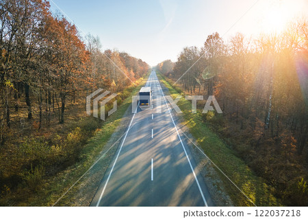 Aerial view of semi-truck with cargo trailer driving on highway hauling goods in evening. Delivery transportation and logistics concept Aerial view of semi-truck with cargo trailer driving on highway hauling goods in evening. Delivery transportation and logistics concept 122037218
