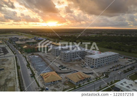 Aerial view of unfinished frames of apartment buildings ready for mounting wooden roof beams under construction. Development of residential housing in american suburbs. Real estate market in the USA 122037258