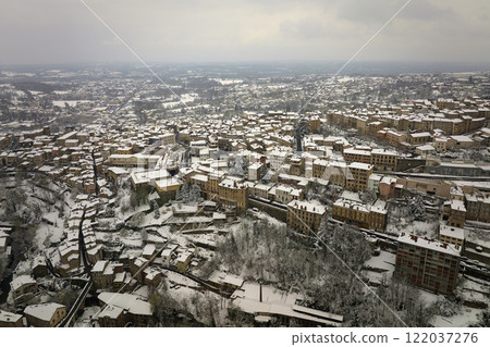 Aerial winter landscape of dense historic center of Thiers town in Puy-de-Dome department, Auvergne-Rhone-Alpes region in France. Rooftops of old buildings and narrow streets at snowfall 122037276