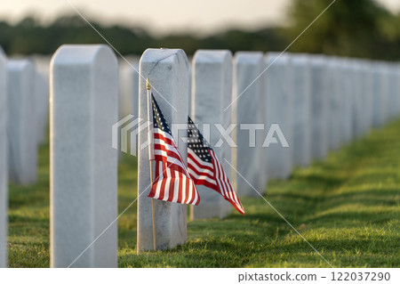 American army national cemetery with rows of white headstones and USA flag on green grass lawn. Memorial Day concept 122037290
