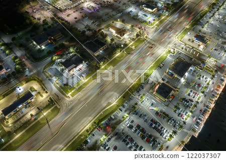 American wide road and strip mall plaza in North Port, Florida. Illuminated town traffic with driving cars at night. USA transportation infrastructure concept 122037307