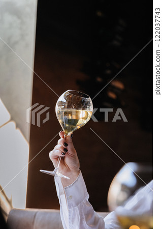 Elegant hand in black gloves holding a wine glass, celebrating luxury and fine dining moments Elegant hand in black gloves holding a wine glass, celebrating luxury and fine dining moments 122037743