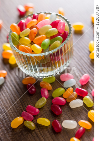 Multicolored jelly beans with various flavors in glass bowl on wooden table. 122037887
