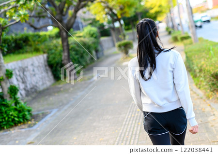 A cool woman walking on a sidewalk in a residential area outdoors Training Diet Exercise 122038441