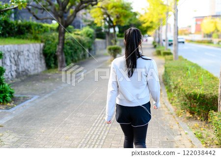 A cool woman walking on a sidewalk in a residential area outdoors Training Diet Exercise A cool woman walking on a sidewalk in a residential area outdoors Training Diet Exercise 122038442