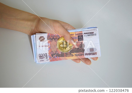 Bitcoin coin and a pack of Russian rubles in a female hand on a white background 122038476