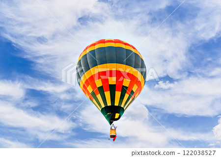 Colorful hot air balloon flying over blue sky with white clouds Colorful hot air balloon flying over blue sky with white clouds 122038527