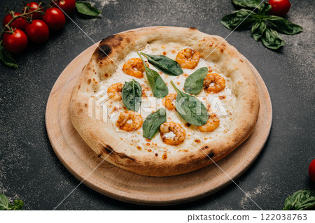 Gourmet shrimp pizza topped with fresh spinach leaves on a golden crust served on a wooden platter 122038763