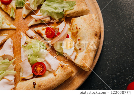 Freshly sliced gourmet salad pizza with lettuce, turkey, and cherry tomatoes on a wooden plate Freshly sliced gourmet salad pizza with lettuce, turkey, and cherry tomatoes on a wooden plate 122038774