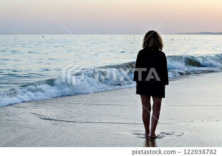 Woman with long hair walking at sunset on the beach of Our Lady of Rocha in Lagoa, Algarve, Portugal. 122038782