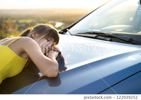 Young female driver resting near her car on warm summer day. 122039252
