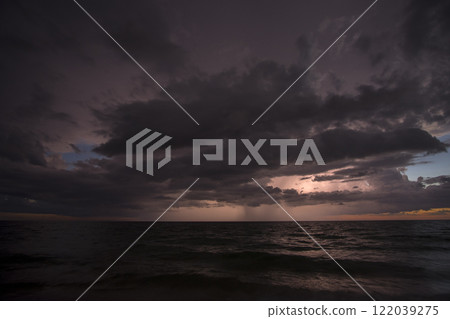 Thunderstorm clouds over rough ocean waters. Evening sea waves crushing on sandy beach. Beautiful seascape at sunset Thunderstorm clouds over rough ocean waters. Evening sea waves crushing on sandy beach. Beautiful seascape at sunset 122039275