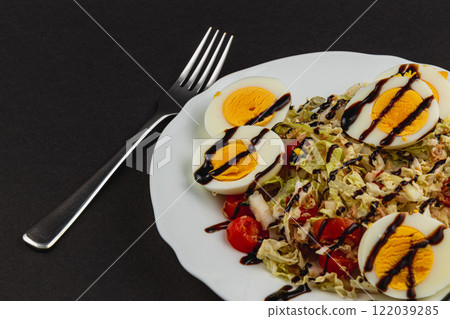 Fresh salad with boiled eggs, tuna, and balsamic dressing on a plate 122039285