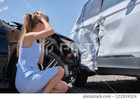 Stressed woman driver standing on street side shocked after car accident. Road safety and insurance concept 122039324
