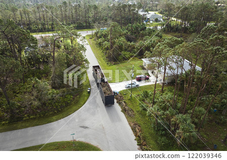 Special aftermath recovery dump truck picking up vegetation debris from suburban streets after hurricane Ian swept through Florida. Dealing with consequences of natural disaster 122039346