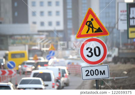 Roadworks warning traffic signs of construction work on city street and slowly moving cars 122039375