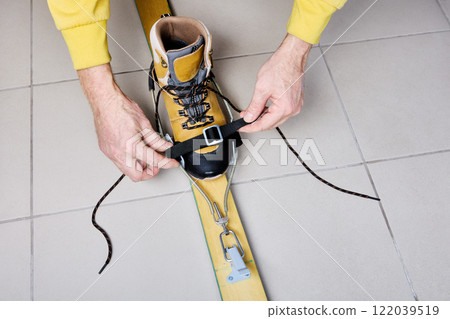 Skier adjusts universal cable ski bindings to fit his boot at home. Skier adjusts universal cable ski bindings to fit his boot at home. 122039519