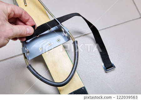 Modern version of universal free heel ski binding Kandahar is attached to wooden touring skis, fitter pushes strap into grooves of bracket. 122039563