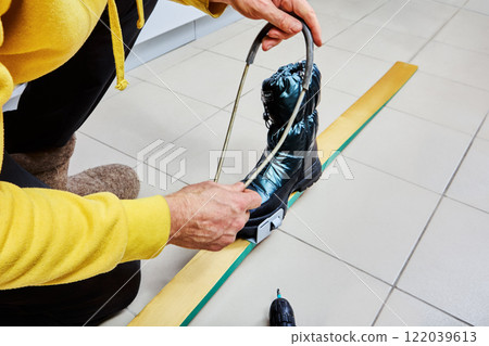 Skier installs spring cable bindings on wooden skis. Skier installs spring cable bindings on wooden skis. 122039613