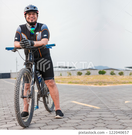 Portrait of cyclist on his bike looking at the camera with copy space. Chubby male cyclist in sportswear riding a bicycle outdoors 122040657