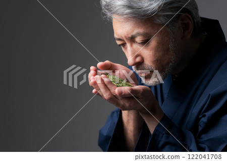 A man in work clothes smelling the aroma of tea 122041708